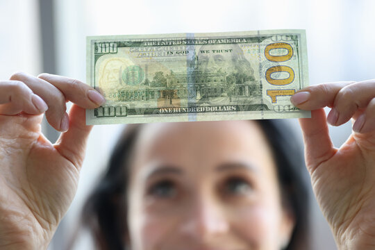 Woman holding dollar bill and looking at it with watermarks closeup