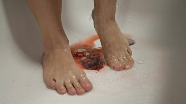 Spontaneous miscarriage in the early stages. Women's feet in the shower. The water washes away the blood.