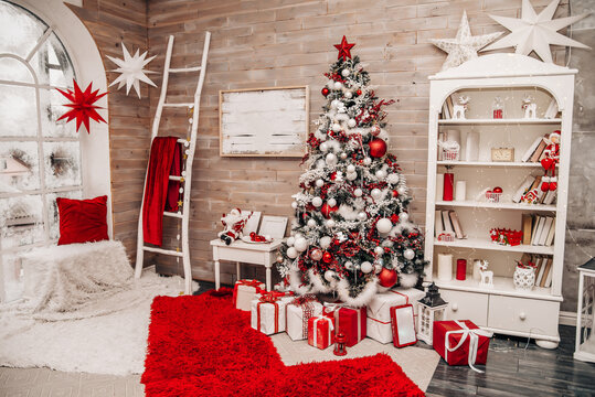 White room with Christmas red decor. Christmas tree, gifts, table and chairs.