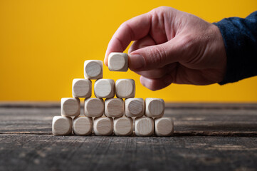 Male hand building a pyramid of wooden dices
