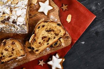 Top view of slice of German Stollen cake, a fruit bread with nuts, spices, and dried fruits with powdered sugar traditionally served during Christmas time on wooden cutting board