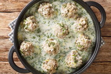 Yuvarlakia is a Greek dish of seasoned meatballs with an Avgolemono or egg lemon sauce sauce close-up in a plate on the table. horizontal top view from above