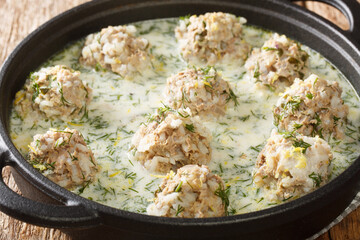 Yuvarlakia is a Greek dish of seasoned meatballs with an Avgolemono or egg lemon sauce sauce close-up in a plate on the table. horizontal