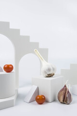 Aesthetic food photography on trendy white podium. Minimal food art still life concept.  Garlic and cherry tomatoes on white background.