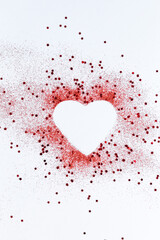 Red confetti glitter in shape of heart on white festive background, copy space, valentines day festive card