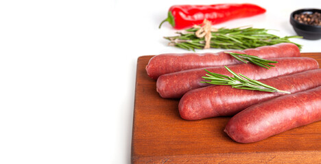 Raw meat beef sausages for grill and spicy, herbs rosemary, pepper, salt on table