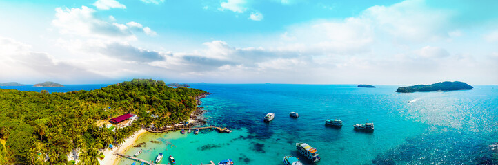 Fototapeta premium Aerial view of beautiful landscape, tourism boats, and people swimming on the sea and beach on May Rut island (a tranquil island with beautiful beach) in Phu Quoc, Kien Giang, Vietnam.