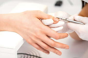 Obraz na płótnie Canvas Manicure master is removing cuticles with a nail clipper in a nail salon