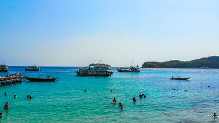 Fototapeta premium Aerial view of beautiful landscape, tourism boats, and people swimming on the sea and beach on May Rut island (a tranquil island with beautiful beach) in Phu Quoc, Kien Giang, Vietnam.