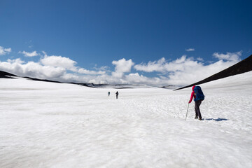 Fototapeta na wymiar Hikers crossing snow covered pass at Eyafjallajökull volcano in the middle of Fimmvorduhals hike, summer in Iceland.