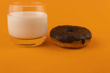 A glass of milk and a chocolate-covered doughnut