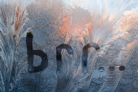 Inscription Brr on the frozen glass. Frosty patterns on window, winter background. Cold weather concept