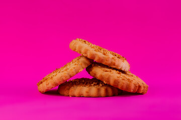 Shortbread cookies sprinkled with slices of hazelnut on a purple background. Delicious homemade cakes made from natural ingredients. Space for text.