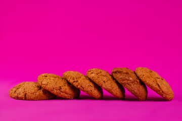 Oatmeal cookies with raisins and nuts inside on a purple background. Delicious homemade cakes made from natural ingredients. Space for text.