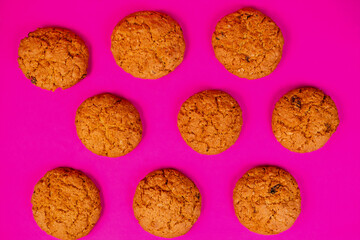 Oatmeal cookies with raisins and nuts inside on a purple background. Delicious homemade cakes made from natural ingredients. Top vew.