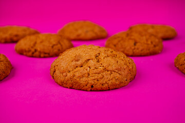 Oatmeal cookies with raisins and nuts inside on a purple background. Delicious homemade cakes made from natural ingredients. Space for text.