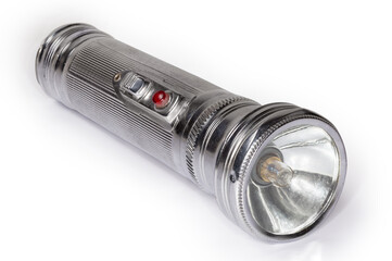 Vintage electric flashlight in metal housing on white background closeup