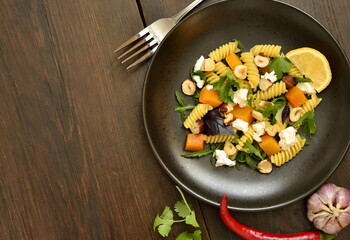 Pasta with baked pumpkin, feta, herbs and hazelnuts,  top view, copy space