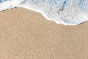 Fototapeta na wymiar Blue wave on sand at the beach shore