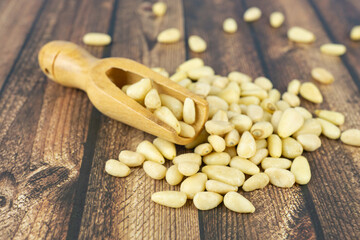 Many pine nuts with wooden spoon and wooden background