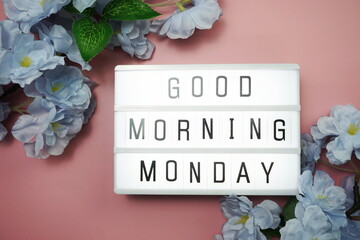 Good Morning Monday word in light box with Flowers Decoration on pink background