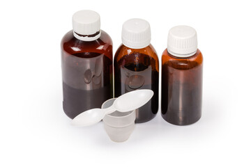 Brown bottles of liquid medicines, measuring cup and measuring spoon