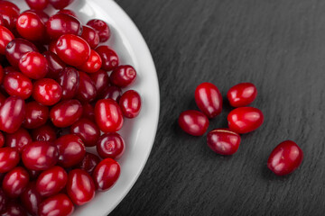 Dogwood berries in a white plate on a black board.