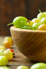 Ripe gooseberry in a wooden plate, place for text