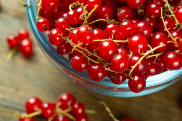 Sweet fresh red currant in a plate on wood table.