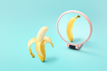 Banana looking at its reflection in mirror on color background