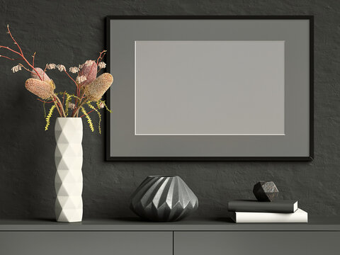 Black mock up picture frame on dark plaster wall with white ceramic vase with flowers, books and geometric pots; landscape orientation; stylish poster mock up background; 3d rendering, 3d illustration