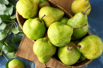 Wicker bowl with fresh ripe pears on table