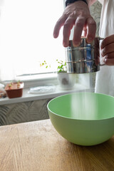 Mesh flour sifter working in cook s hand. Background with free copy text space. Preparation of dough for dumplings.