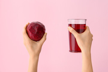 Hands with glass of beetroot juice on color background