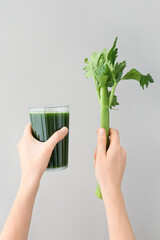 Hands with glass of celery juice on grey background