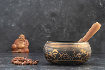 Singing bowl with wooden stick and tibetan beaded rosary on gray background