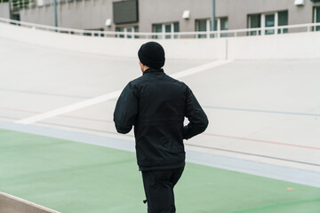 Athletic sportsman running while working out at stadium