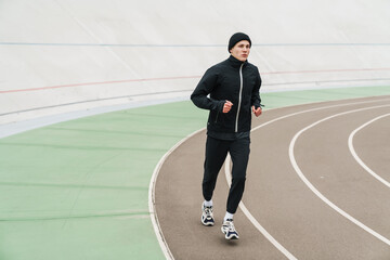 Young sporty man running at the stadium