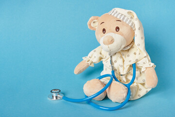 cute teddy bear and stethoscope on blue background