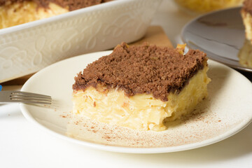 Hanukkah holiday, traditional sweet Kugel pie with noodles and custard, shortbread cocoa crumbs on top. on a light background in a baking dish. pie slices on a plate