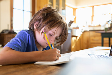 Young boy at home writing and drawing in his drawing pad