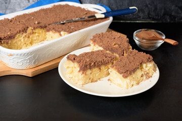 Hanukkah holiday, traditional sweet Kugel pie with noodles and custard, shortbread cocoa crumbs on top. on a light background in a baking dish. pie slices on a plate