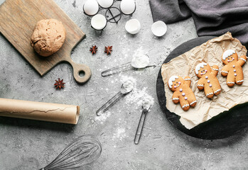 Tasty gingerbread cookies with ingredients on grey background