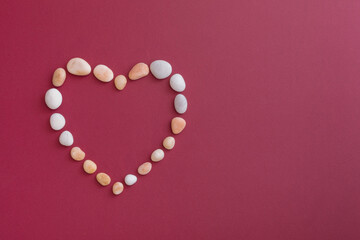A heart made of pebbles for Valentine's Day  on a red background with copy space
