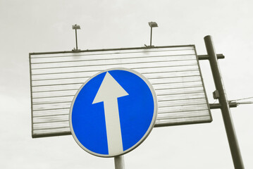 Blue traffic sign and an empty metal advertisement board.