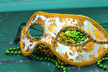 Mardi gras mask and beads on a wooden background. Madi Gras carnival accessories, confetti,...