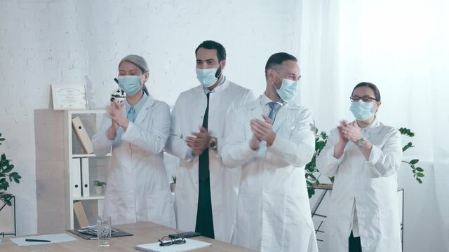 multicultural doctors in medical masks applauding during conference