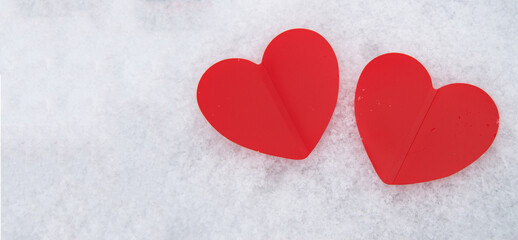 Obraz na płótnie Canvas Two beautiful romantic red hearts together on a white snowy background. The concept of love and Valentine's Day