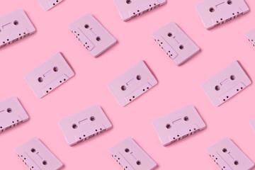 Pattern made with retro audio cassettes on modern pink background. Creative concept of retro technology. 70's or 80's aesthetic. Flat lay, top view.