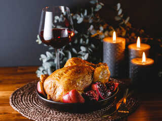 Fototapeta na wymiar Whole roast chicken with pomegranate, apple and red wine on a festive table. Christmas or New Year cooking concept.